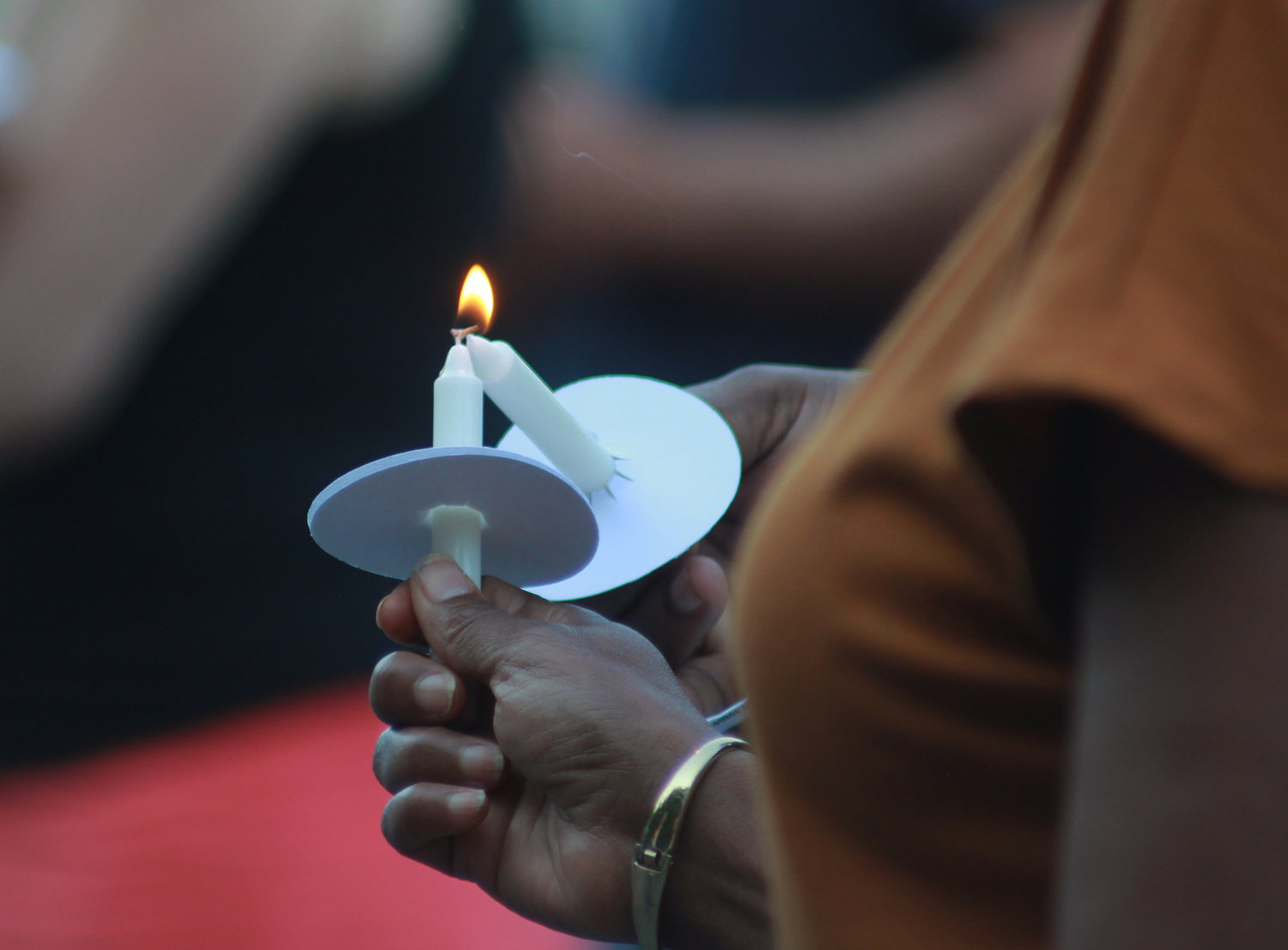 Participants of the Chatham County vigil for recent mass shootings help one another light their candles on Sunday, May 29, in Pittsboro.